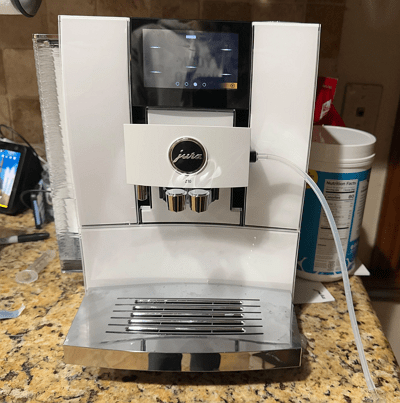 Jura E6 super-automatic espresso machine in piano black with dual spouts.