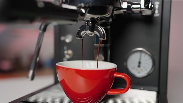 Close-up of La Pavoni Mini Cellini pulling a double espresso into a red cup.