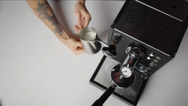 Top-down view of a milk pitcher positioned on the Mini Cellini steam wand.