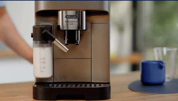 De’Longhi Magnifica Evo super-automatic espresso machine with milk carafe attached on a kitchen counter